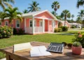 A bright coral and white Florida home with palm trees and a renewal letter and calculator on the porch, showing florida homeowners insurance rates in daylight.